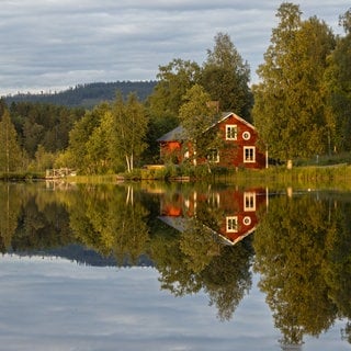 Rotes Holzhaus am See in Schweden