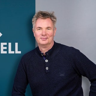 Gerald Pinkenburg steht vor dem Logo von SWR Aktuell.