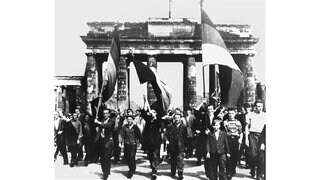Ost-Berliner marschieren am 17 Juni 1953 mit wehenden Fahnen vom Ost-Sektor aus durch das Brandenburger Tor. Nach Streiks in Ost-Berlin kam es zum Volksaufstand, der von sowjetischen Truppen niedergeschlagen wurde.