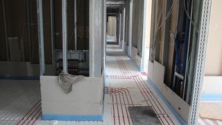 Ein Rohbau mit einer offenen Fußbodenheizung in einer Schule. Sie kühlt im Sommer mit Regenwasser.