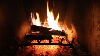 In einem Kamin flackert ein Feuer.