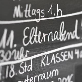 Das Wort "Elternabend" steht in einer Grundschule an einer Tafel. 