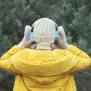 Eine Frau hört draußen Musik mit Kopfhörern
