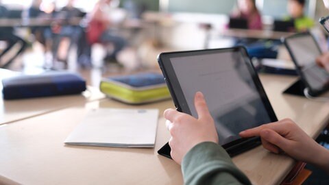 In einer 3. Klasse einer Grundschule lösen Schüler an Tabletts digitale Mathematikaufgaben.