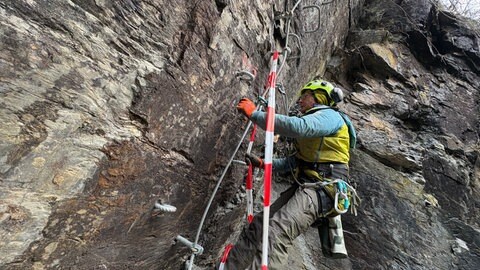 Patrick Jost hängt mit einem Seil in einer Felswand in Neuerburg. Er hat mit seiner Firma schon 12 Klettersteige gebaut. Meist in den Alpen, aber auch schon in Berlin.