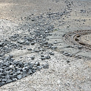 Eine Straße mit Löchern und Splitt (Symbolbild).