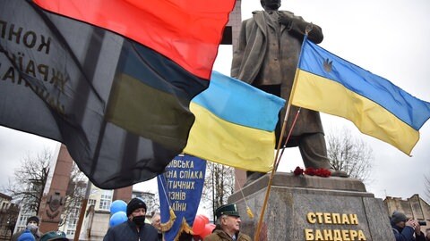 Menschen mit Fahnen in der Nähe des Denkmals für Stepan Bandera in Lwiw während der Feierlichkeiten zu dessen 113. Geburtstag am 1. Januar 2022