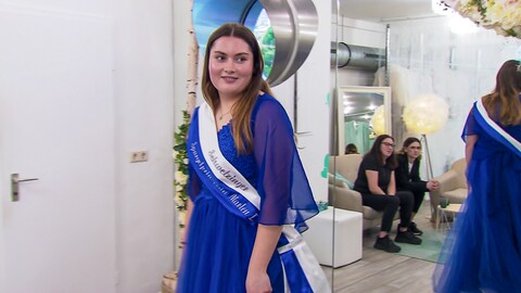 Marlen trägt ein blaues Kleid und eine Schärpe mit der Aufschrift „Schwetzinger Spargelprinzessin Marlen I.“.