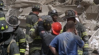 Feuerwehrleute durchsuchen die Trümmer, nachdem Terroristen am Dienstag, den 11. September 2001, zwei Flugzeuge in das World Trade Center in New York steuerten und die Türme zum Einsturz brachten