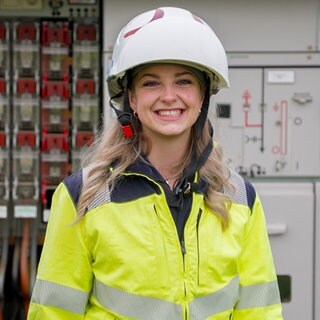 Vivienne steht ihn ihrer Arbeitskleidung vor einer Umspannstation, bei der sie gerade den Strom abgestellt hat. Sie arbeitet als Elektronikerin für Betriebstechnik und plädiert für mehr Frauen im Handwerk.