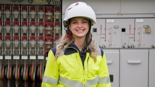 Vivienne steht ihn ihrer Arbeitskleidung vor einer Umspannstation, bei der sie gerade den Strom abgestellt hat. Sie arbeitet als Elektronikerin für Betriebstechnik und plädiert für mehr Frauen im Handwerk.