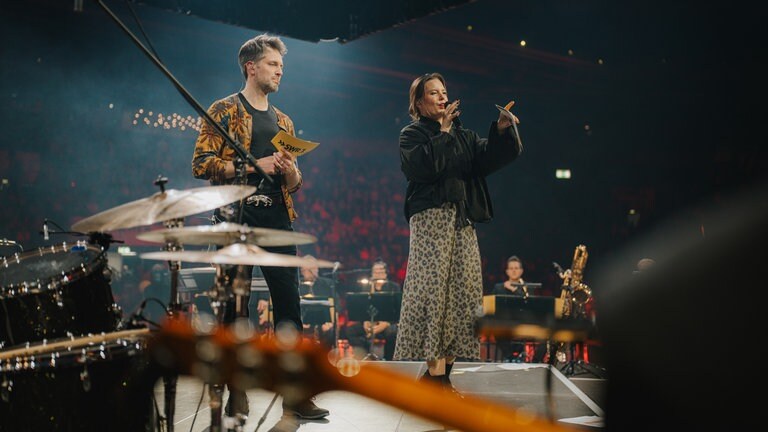 Finale der SWR1 Hitparade 2025 mit Benedict Walesch und Cora Klaunitzer, beide moderieren auf der Bühne
