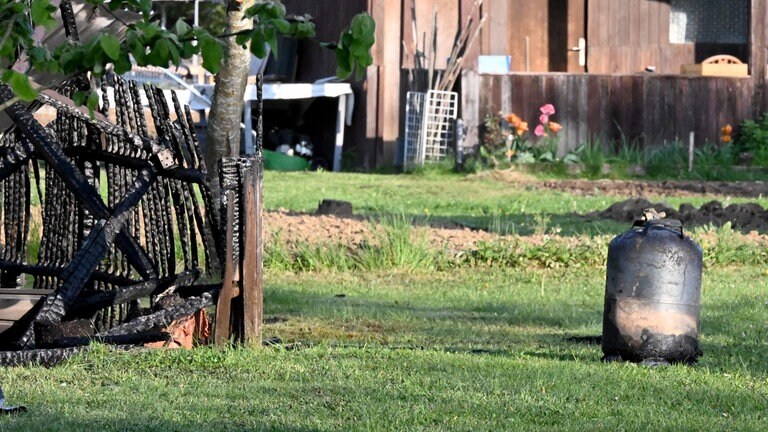 Verkohlte Holzreste. Wegen Explosionsgefahr mussten die Feuerwehrleute Gasflaschen aus den brennden Hütten holen. Acht Gartenhütten haben am Montagmorgen in Langenau gebrannt. 