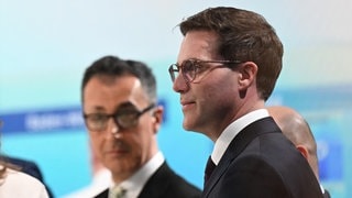 Cem Özdemir und Manuel Hagel stehen in einem Fernsehstudio. Die CDU will Gespräche mit den Grünen aufnehmen.