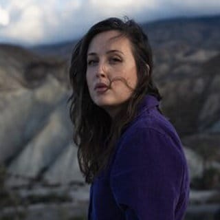 Die deutsch-britische Popmusikerin Alice Merton steht mit vom Wind zerzaustem Haar vor einer Gebirgstkette. | Alice Merton: "Für die Nibelungen habe ich direkt Ja gesagt"