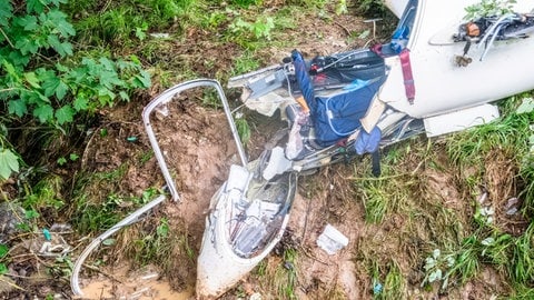Ein Segelflugzeug liegt nach einem Absturz am Rande einer Waldlichtung - der Crash hat das Cockpit komplett in seine Einzelteile zerlegt. SWR1 Neuanfang: Alex überlebt den Absturz mit dem Segelflieger – die Sehnsucht nach Höhe und Weite bleibt