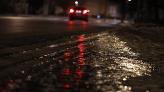 Ein Auto fährt in der Nacht auf einer vereisten Straße. Polizei und Wetterdienst in BW warnen vor Glatteis.