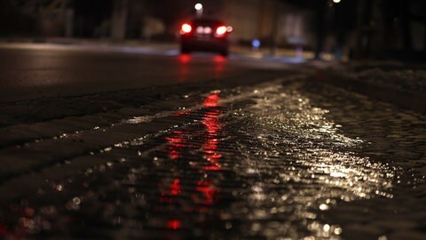Ein Auto fährt in der Nacht auf einer vereisten Straße. Polizei und Wetterdienst in BW warnen vor Glatteis.
