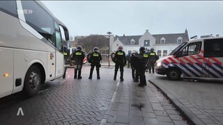 Polizisten stehen neben einem Bus