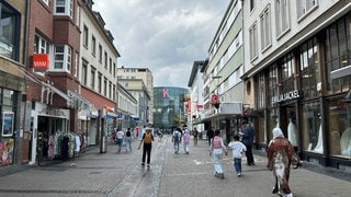 Eine Frau mit Kopftuch läuft in der Fußgängerzone in Kaiserslautern in Richtung der Mall.