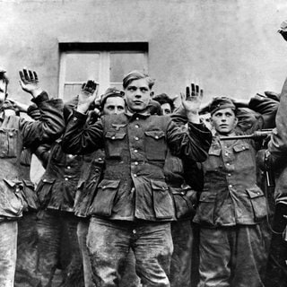 Junge deutsche Soldaten werden von einem amerikanischen Soldaten bewacht. 