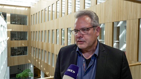 Tübingens Baubürgermeister Cord Soehlke steht im Technischen Rathaus und wird interviewt. Zwei junge Männer wehren sich gegen Mietwucher in Tübingen.