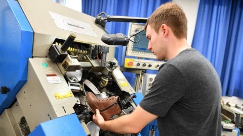 Ein Auszubildener an einer Maschine zur Schuhfertigung.