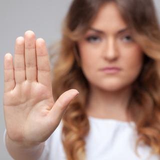 Eine Frau schaut in die Kamera und hält ihre Hand hoch.