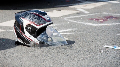 Ein Motorradhelm liegt auf einer Straße. Die Zahl der verletzten Motorradfahrer verharrt in Rheinland-Pfalz auf hohem Niveau (Symbolbild)