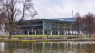 Weitwinkelaufnahme des Landtags von Baden-Württemberg in Stuttgart kurz vor der Landtagswahl 2026 mit Blick über den Eckensee. Vor dem Gebäude sind Menschen zu sehen, im Hintergrund der Stuttgarter Fernsehturm. (Symbolbild)