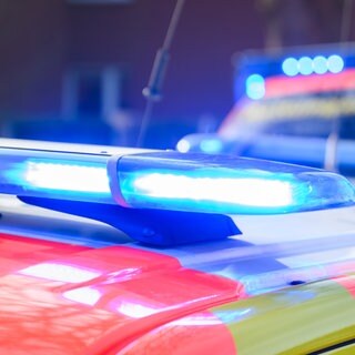 Blaulichter leuchten an einer Einsatzstelle auf einem Notarzt-Fahrzeug und einem Rettungswagen. Symboldbild für: Mann stirbt bei Hausbrand in Homburg.