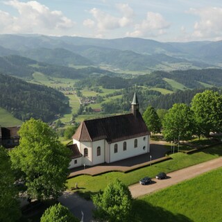 Kirche in einer grünen, ländlichen Landschaft.