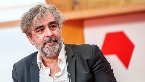 Deniz Yücel, Journalist, blickt zu einem Gesprächspartner.