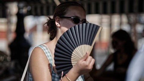 Eine junge Frau mit Sonnenbrille und Fächer.