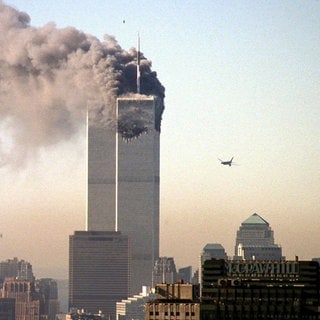 Ein Turm des World Trade Centers brennt am 11. September 2001 in New York, schwarze Rauchwolken steigen auf. Ein zweites Flugzeug ist im Anflug auf den zweiten Turm: Wie hat sich der Islamismus in Deutschland nach 911 entwickelt?