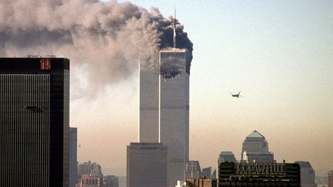 Ein Turm des World Trade Centers brennt am 11. September 2001 in New York, schwarze Rauchwolken steigen auf. Ein zweites Flugzeug ist im Anflug auf den zweiten Turm: Wie hat sich der Islamismus in Deutschland nach 911 entwickelt?