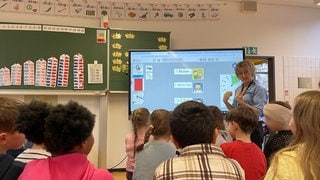 Lehrerin Simone Kühn steht vor ihrer 1. Klasse im Klassenraum in der Grundschule "Am Lemmchen" in Mainz-Mombach.