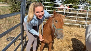 Madeleine „Maddy“ Morhardt steht mit einem Pferd in einer Kuppel. Sie lächelt in die Kamera.