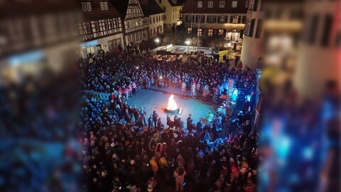 Die Menschenmenge erwartet die Hutschelhexen auf dem Schlossplatz. Zum Start der Fastnacht wird in Bad Bergzabern eine große Feuerschale entzündet.