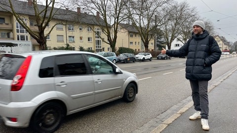 Ein junger Tramper hofft auf eine Mitfahrgelegenheit in Freiburg-Littenweiler