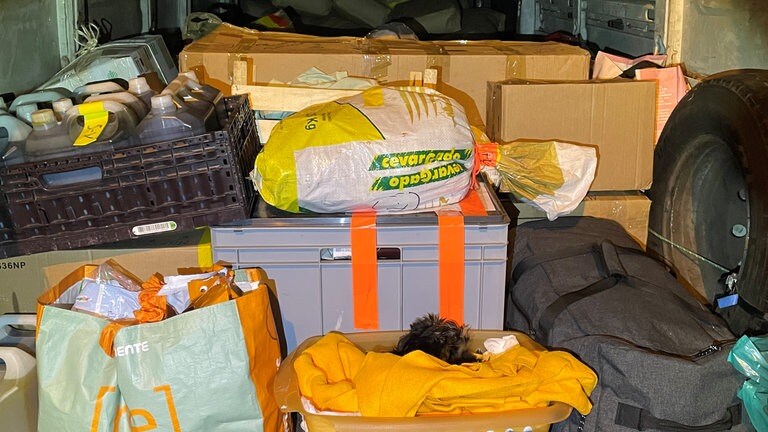Zwischen Kisten und Taschen liegt ein Hundewelpe in einem Korb.