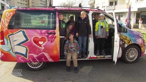 Kinder sitzen in einem neuen Herzensbus