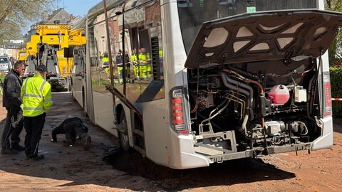 Nach einem Wasserrohrbruch in der Medardstraße in Trier hat sich ein Linienbus festgefahren. Ein Kran half bei der Bergung.
