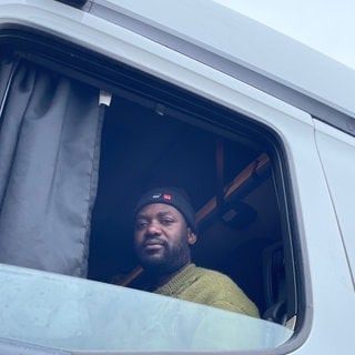Adam M., Lkw-Fahrer aus Simbabwe, sitzt in seinem Führerhaus. Er demonstriert seit Tagen in Karlsruhe gegen seinen Arbeitgeber.