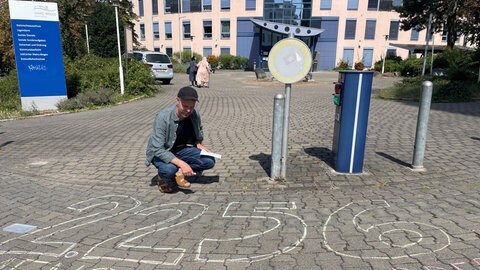 Petitions-Initiator Nicolas Krahwinkel hat vor der Kreisverwaltung die Zahl der Unterschriften auf den Bürgersteig gemalt.