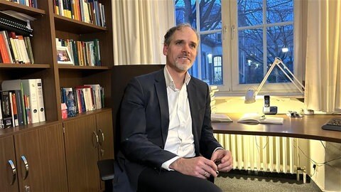 Professor Pagonis sitzt in seinem Büro, tags: Lernen, KI, Sprache, Sprachlehrer