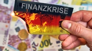 Brennende Geldscheine mit Aufschrift "Haushaltsloch"