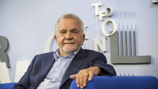 Rüdiger Safranski bei der Frankfurter Buchmesse 2015. Er sitzt in einem blauen Sessel, im Hintergrund eine hellblaue Wand mit Buchstaben.