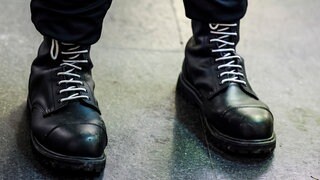 Ein Teilnehmer einer rechtsextremen Kundgebung trägt schwarze Springerstiefel mit weißen Schnürriemen, ein weit verbreitetes Symbol der rechten Szene.