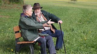 Hermann und Johanna sitzen auf einer Bank auf der grünen Wiese